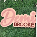 Layered first and middle name sign displayed on a greenery wall as a baby shower backdrop