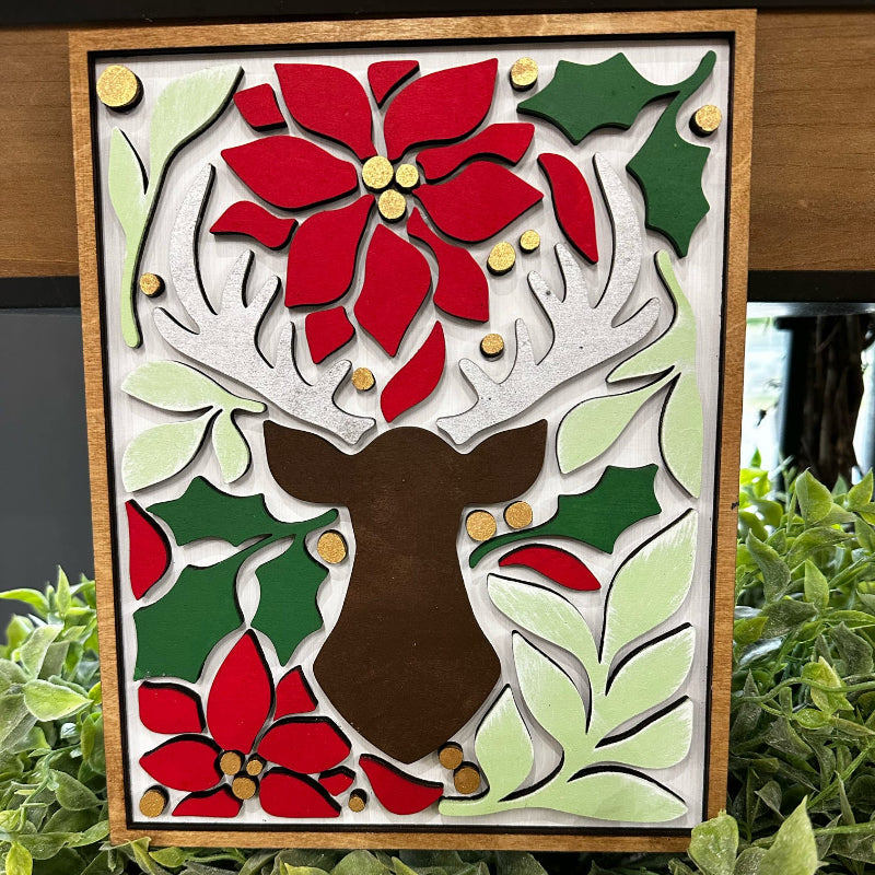 A 3D layered Christmas decoration featuring a reindeer design with poinsettia flowers and holly in red, green, and white colors.