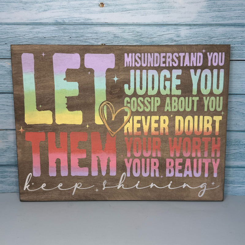 Wooden sign with motivational quote in rainbow colors on a wooden background