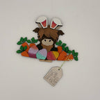 Decorative item with a character wearing bunny ears, surrounded by Easter eggs and carrots, on a white background.