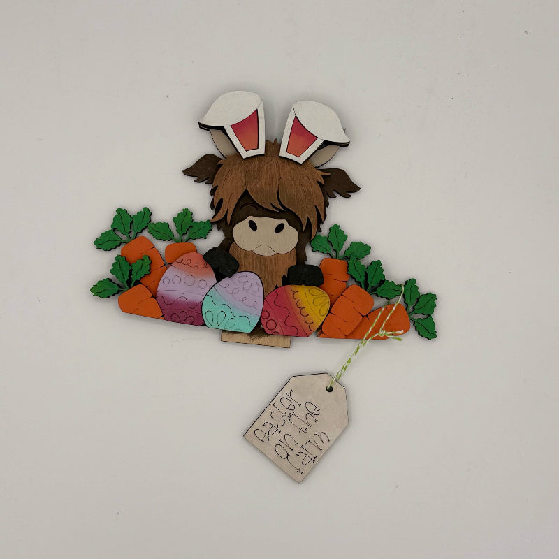Decorative item with a character wearing bunny ears, surrounded by Easter eggs and carrots, on a white background.