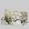 Wooden beach-themed cutouts including a sandcastle, umbrella, surfboard, and toys on a wooden surface.