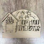 Wooden decorative sign with doghouse design and text on a wooden surface