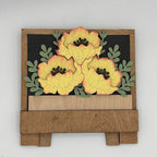 Wooden wall art with yellow flowers and green leaves on a white background