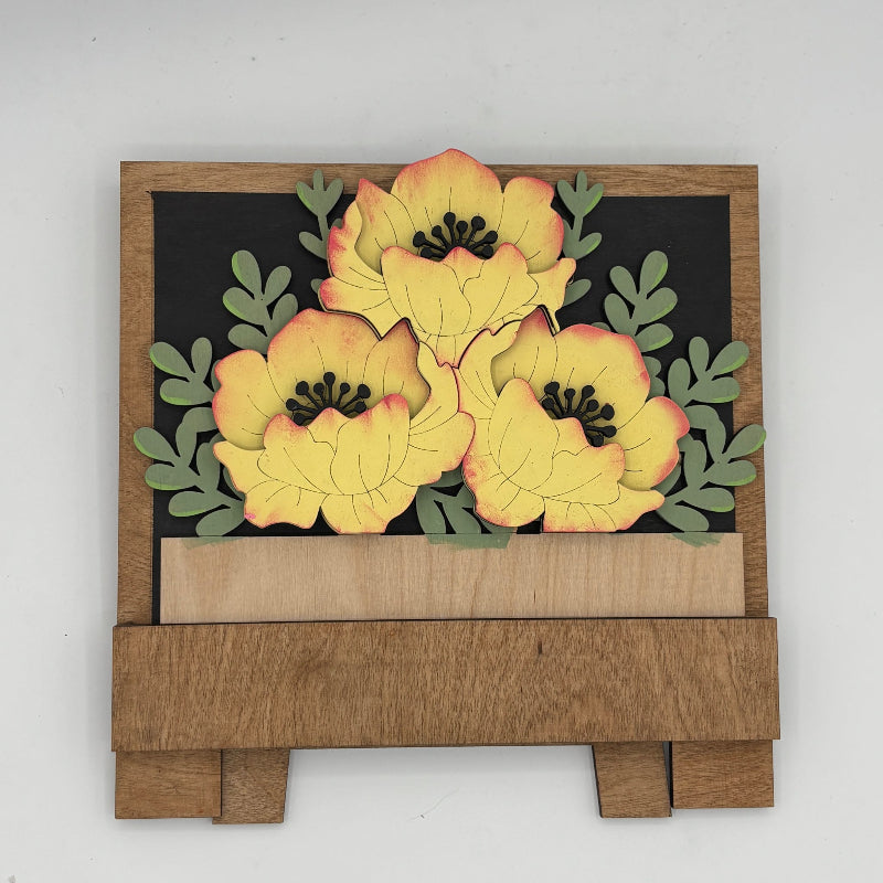 Wooden wall art with yellow flowers and green leaves on a white background