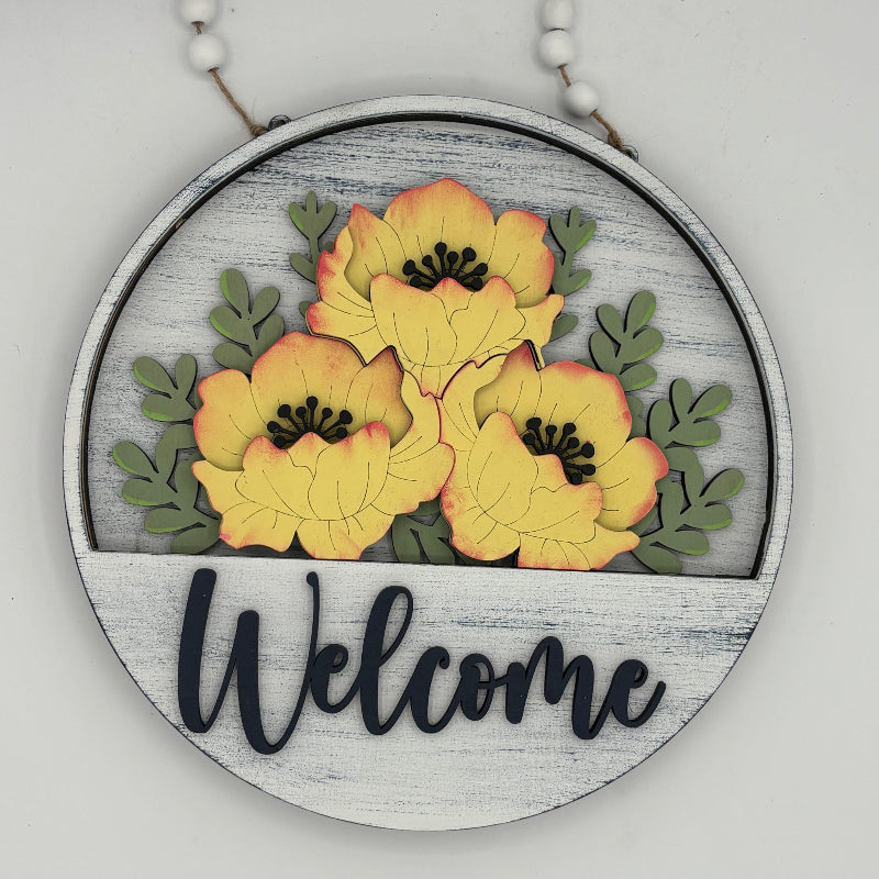 Decorative sign with yellow flowers and 'Welcome' text on a wooden hoop.