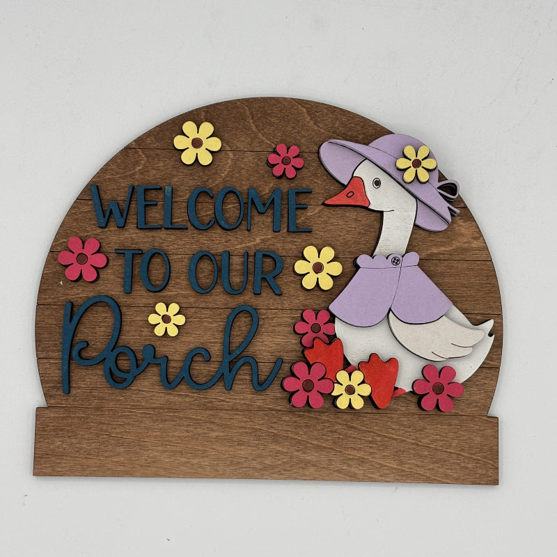 Decorative sign with a goose illustration and 'Welcome to our Porch' text on a wooden background.