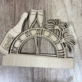 Wooden New Year's Eve decoration with champagne glasses, palm trees, and 'Happy New Year' text on a wooden surface.