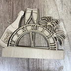 Wooden New Year's Eve decoration with champagne glasses, palm trees, and 'Happy New Year' text on a wooden surface.
