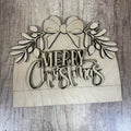 Wooden 'Merry Christmas' decoration with a bow and foliage on a wooden surface