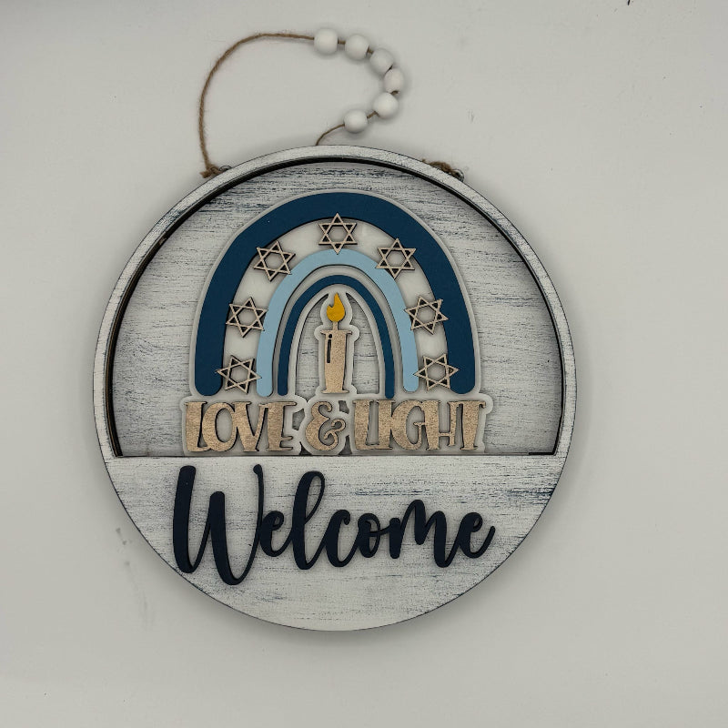 Decorative hanging sign with 'Love & Light Welcome' text on a white background