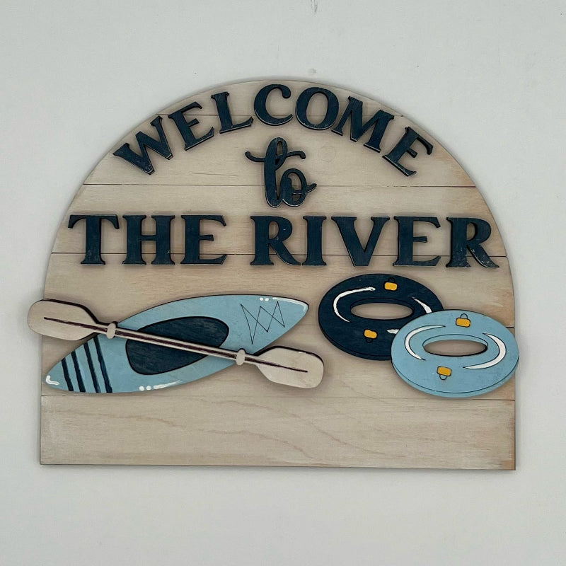 Decorative sign with 'Welcome to The River' text and kayak, paddle, and life jacket illustrations on a white background.