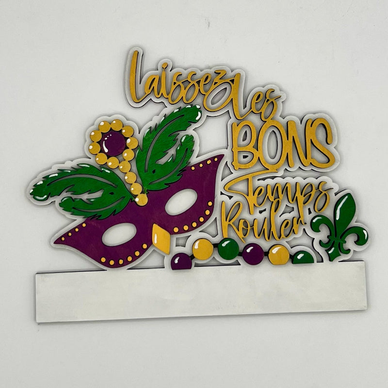 Decorative sign with Mardi Gras mask and text on a white background