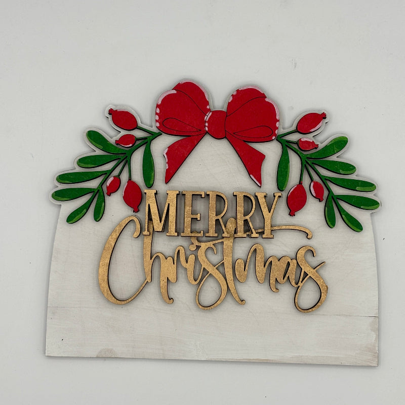 Decorative Christmas sign with red bow, green leaves, and 'Merry Christmas' text on a white background.
