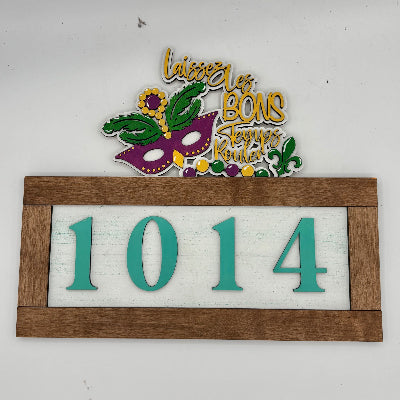 Decorative sign with a Mardi Gras mask and numbers '1014' on a white background