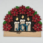 Decorative wall art with poinsettias, candles, and 'JOY' letters on a white background