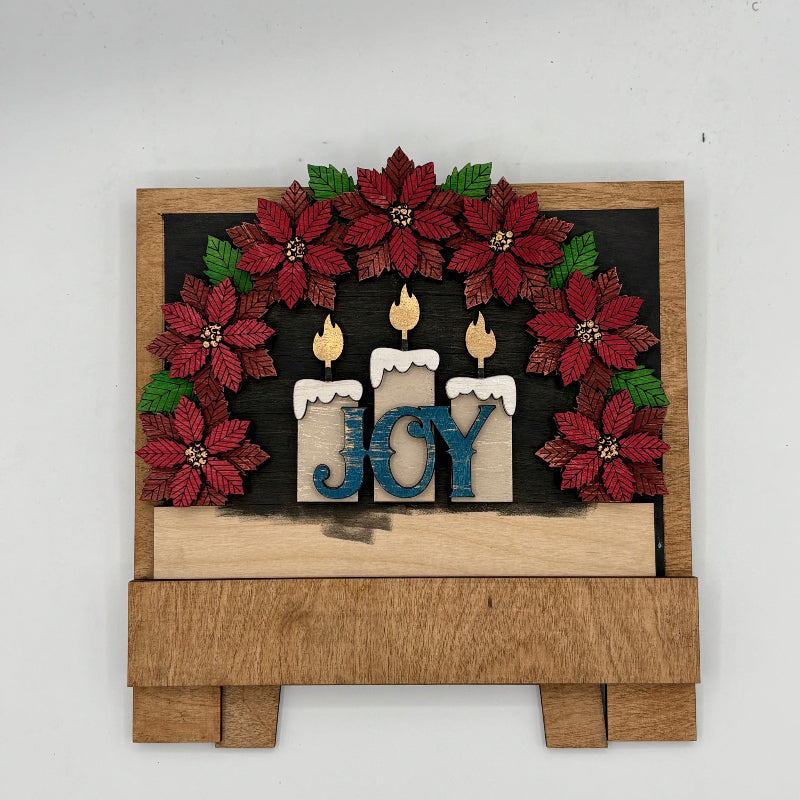 Decorative wall art with poinsettias, candles, and 'JOY' text on a wooden base.