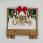 Decorative Christmas sign with 'Merry Christmas' text, red bow, and green leaves on a white background.