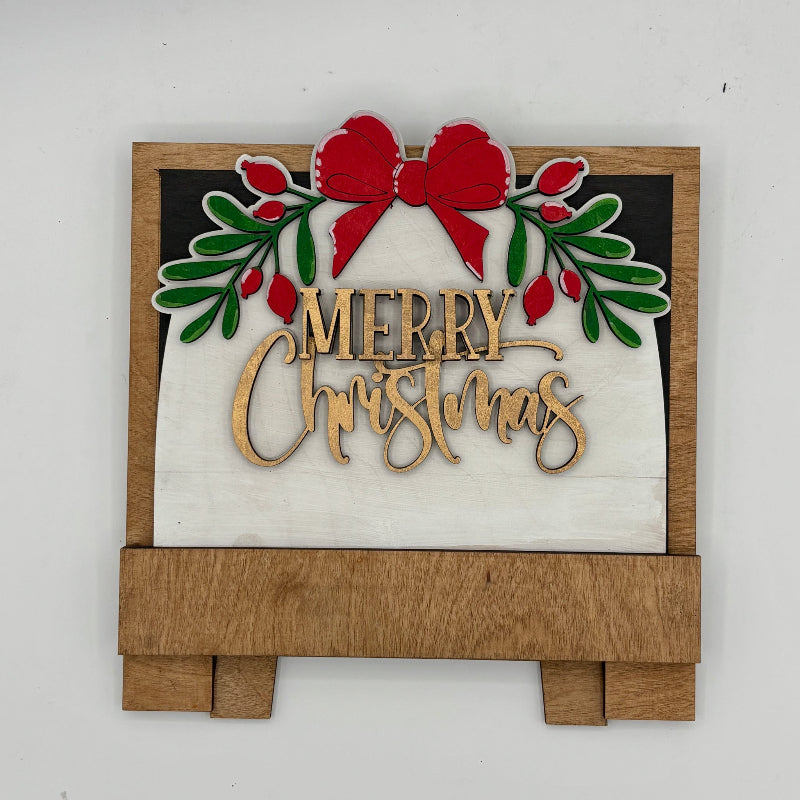 Decorative Christmas sign with 'Merry Christmas' text, red bow, and green leaves on a white background.