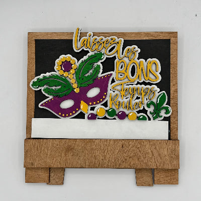 Decorative sign with Mardi Gras mask and text on a white background