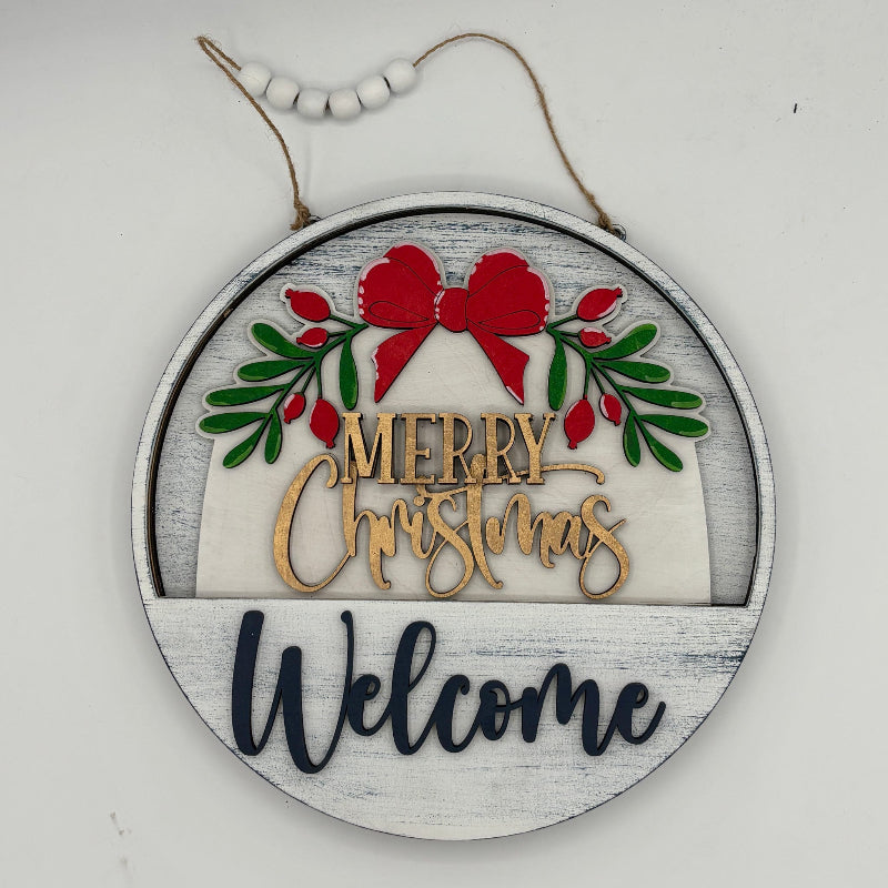 Round wooden ornament with 'Merry Christmas Welcome' text and festive design on a white background