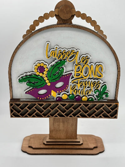 Decorative sign with Mardi Gras-themed design and wooden frame on a white background
