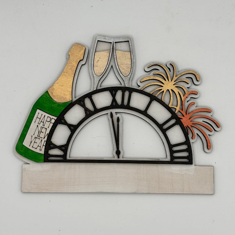 Decorative wall art with New Year's Eve elements including a bottle, glasses, clock, and fireworks on a white background.