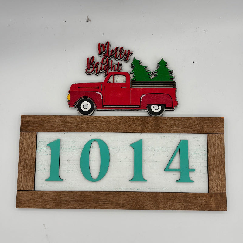 Decorative sign with red truck, Christmas trees, and house numbers '1014' on a white background.