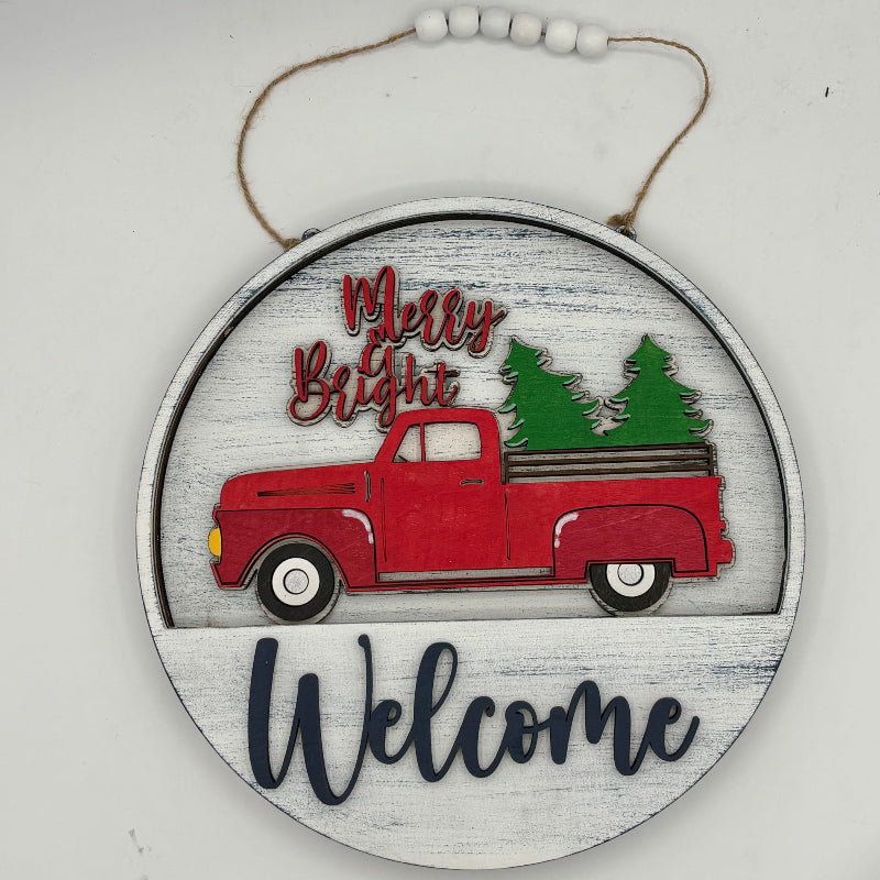 Decorative sign with a red truck and Christmas trees, featuring 'Merry & Bright Welcome' text.