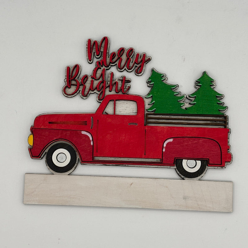 Decorative sign with a red truck, Christmas trees, and 'Merry Bright' text on a white background.