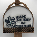 Decorative sign with 'Serving Unselfishly and Continuously' text and emblem on a white background