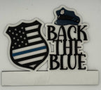 Decorative sign with 'Back the Blue' text and American flag design on a white background