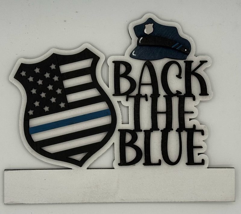 Decorative sign with 'Back the Blue' text and American flag design on a white background