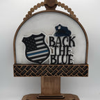 Decorative sign with 'Back the Blue' text and American flag design on a white background