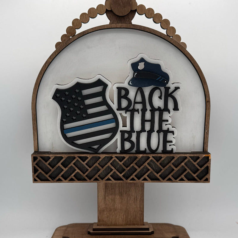 Decorative sign with 'Back the Blue' text and American flag design on a white background