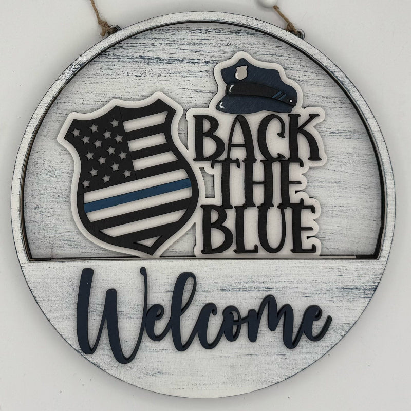 Decorative sign with 'Back the Blue' and 'Welcome' text on a wooden background