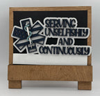 Decorative sign with text 'Serving Unselfishly and Continuously' on a wooden base.