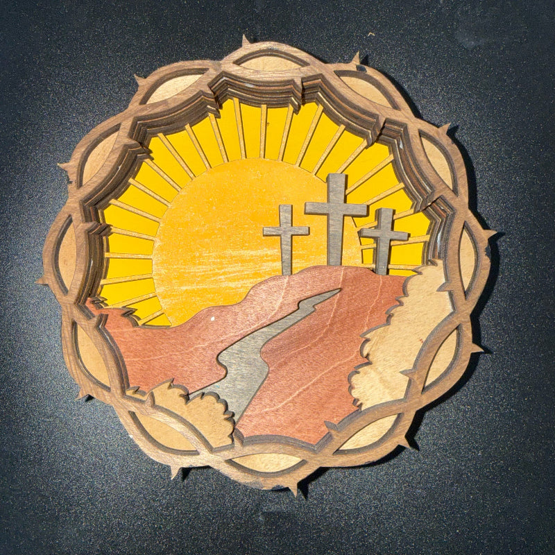 Wooden cutout with three crosses and a sunburst design on a dark background