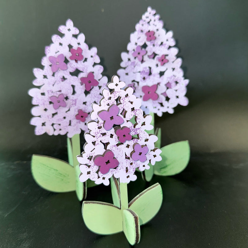 Decorative brooch with purple flowers and green leaves on a dark background