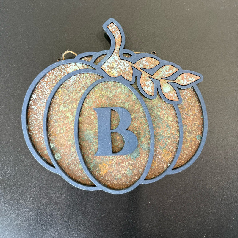 Decorative pumpkin-shaped ornament with letter 'B' on a dark background