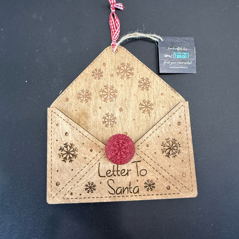 Decorative envelope ornament with 'Letter to Santa' text and snowflake patterns on a dark background.