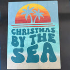 Wooden sign with 'Christmas by the Sea' text and palm tree design on a gradient background.
