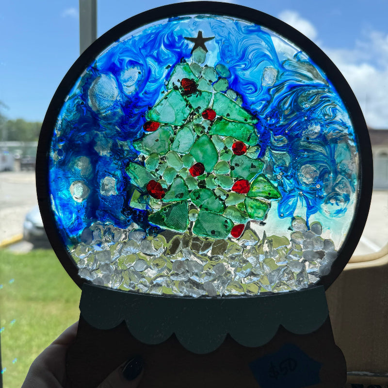 Decorative glass panel with a Christmas tree design on a window