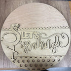 Wooden round sign with 'Let's Flamingle' text and flamingo design on a wooden surface.