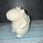 White ceramic hippo figurine on a wooden surface with a dark background