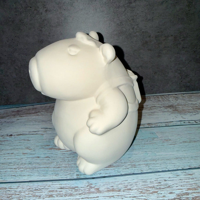 White ceramic hippo figurine on a wooden surface with a dark background