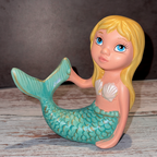 Mermaid figurine with a shell on a wooden surface
