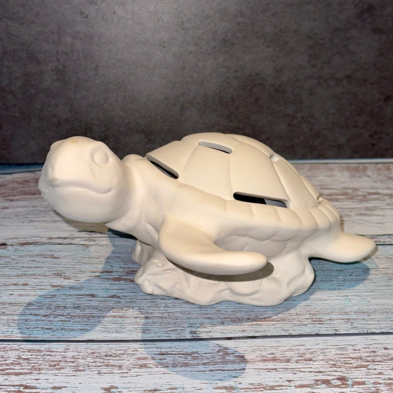 White ceramic turtle-shaped money box on a wooden surface with a gray background