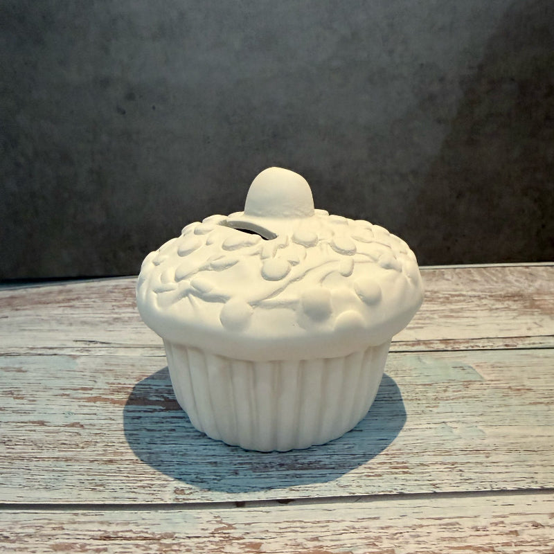 White ceramic cupcake-shaped container on a wooden surface with a gray background