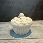 White ceramic cupcake-shaped container on a wooden surface with a gray background